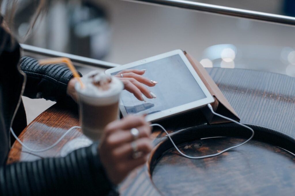 Person using a tablet in a café, checking whether a product still solves the right problem