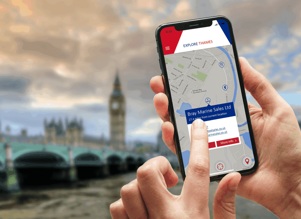 Explore Thames tourism app on a phone in front of the Houses of Parliament