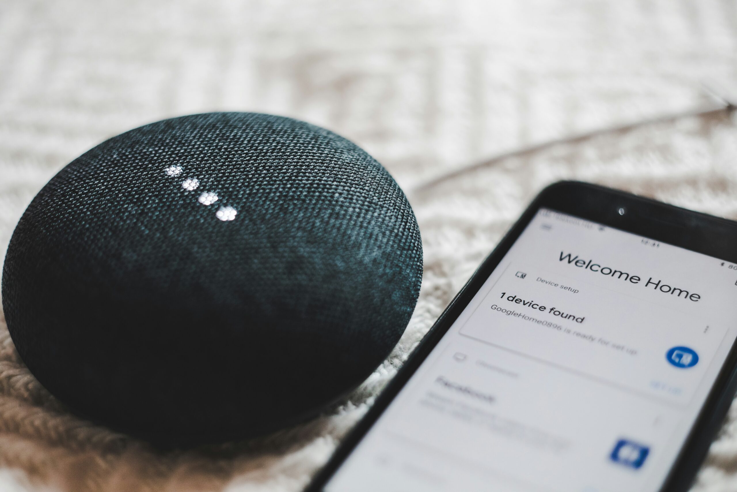 Google Home Mini next to smartphone setting up Google Home app for smart home