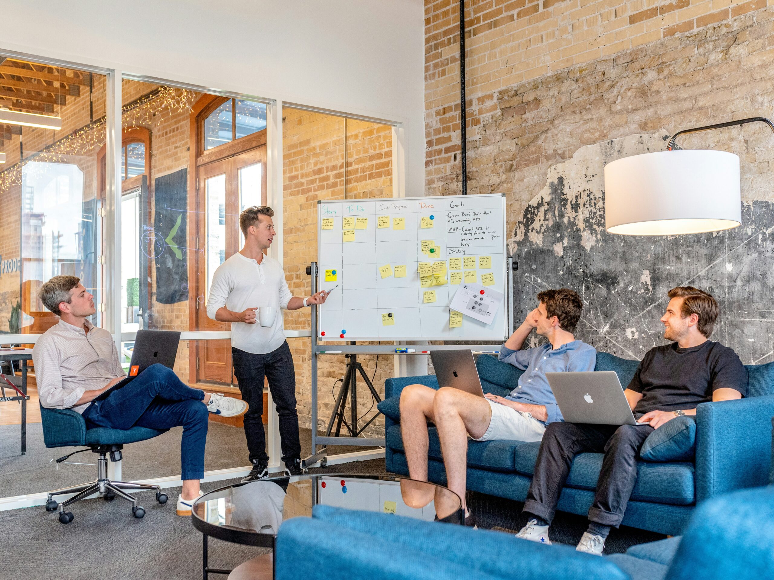 Startup team meeting brainstorming at whiteboard with sticky notes, agile sprint planning