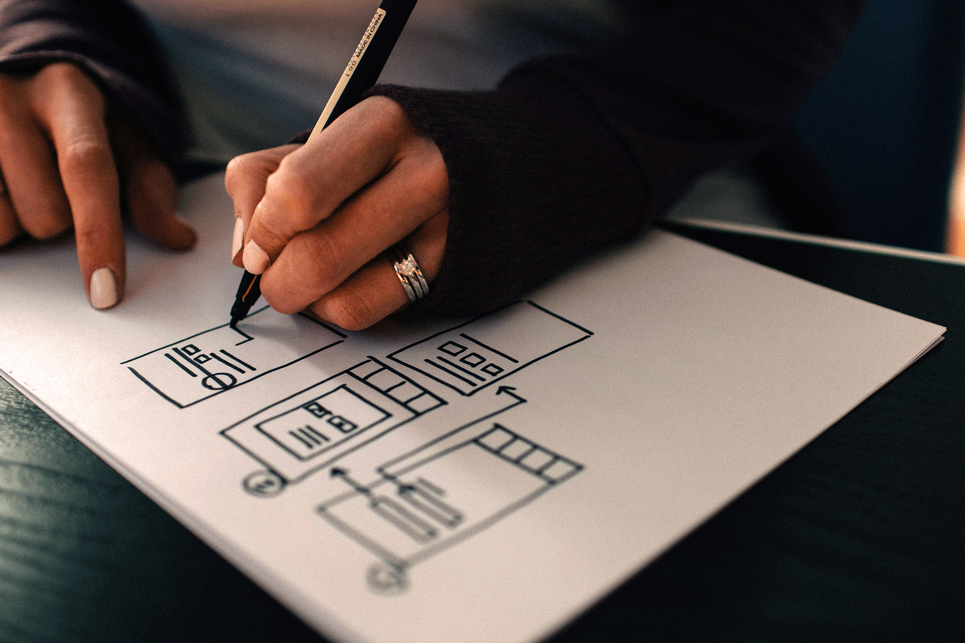 Sketching UX UI wireframe for website on paper with pen