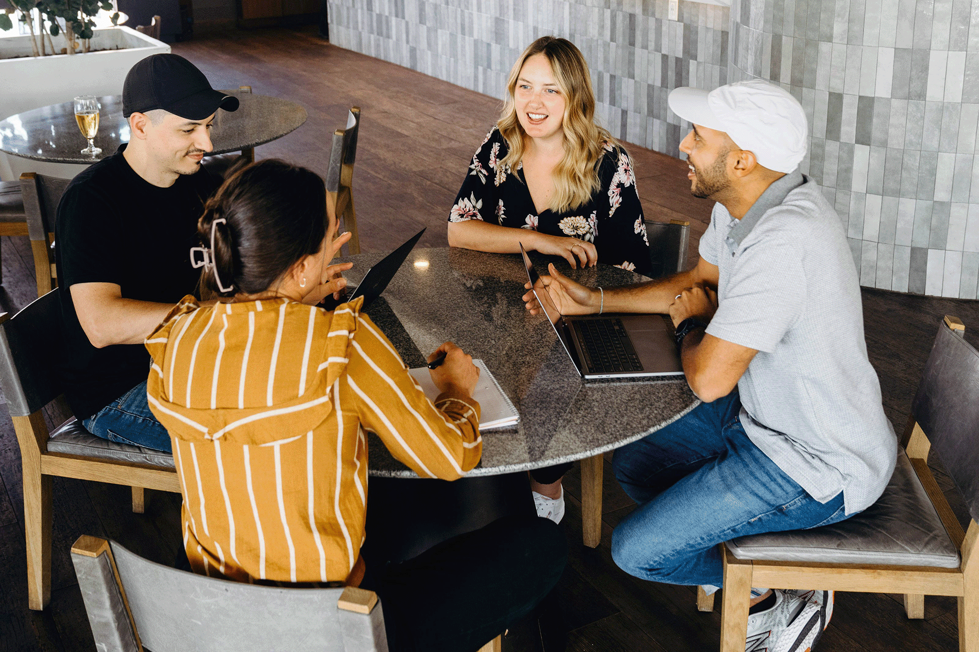 Coworkers in casual team meeting, collaborating with laptops around a round table in modern office