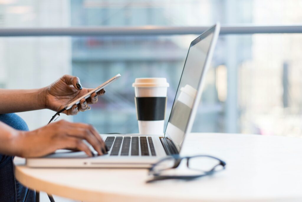 Person on a phone and laptop in a café, an account manager keeping in touch with clients