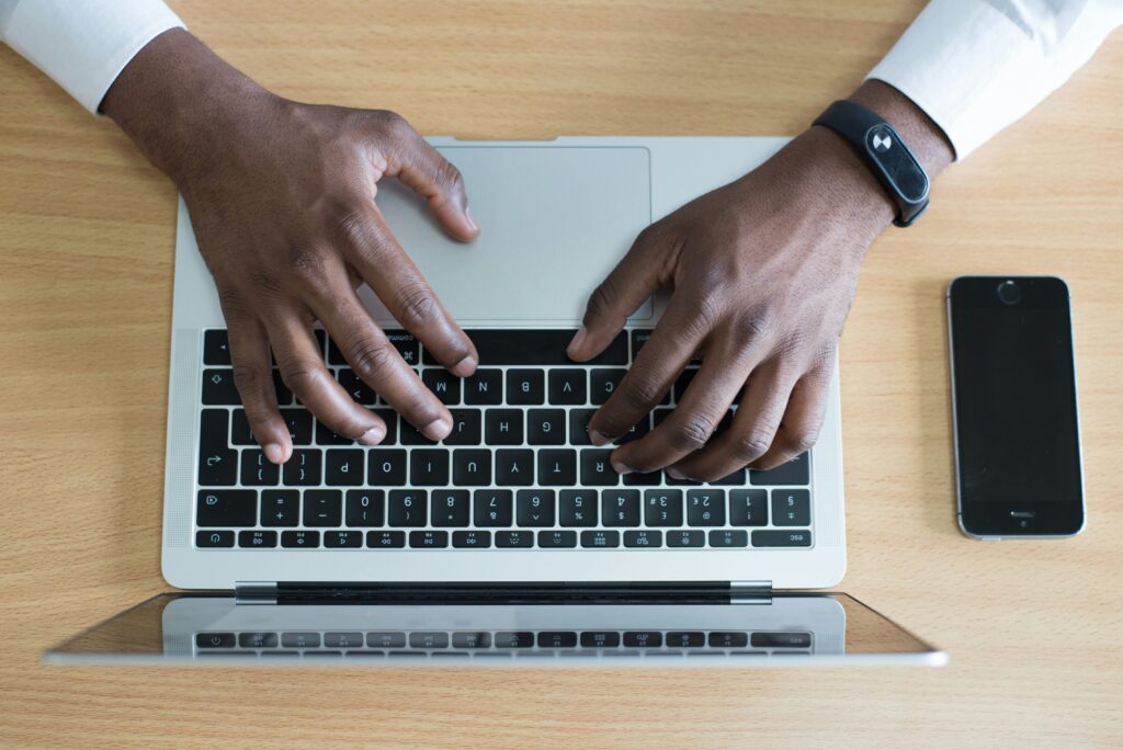 Hands typing on a laptop beside a phone, a day in the life of an account manager
