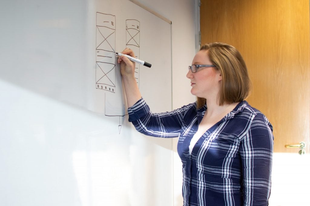 Designer sketching app wireframes on a whiteboard