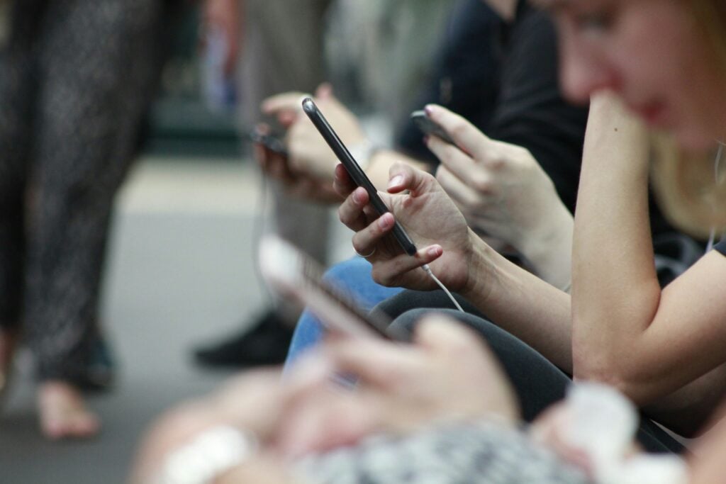 Group of people using their phones, the users digital products need to win over to close the adoption gap