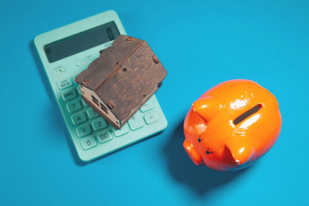 Calculator, model house and piggy bank representing digital investment in financial services