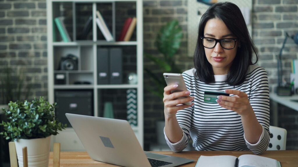 Woman paying online with a card and phone, as user payment expectations move on