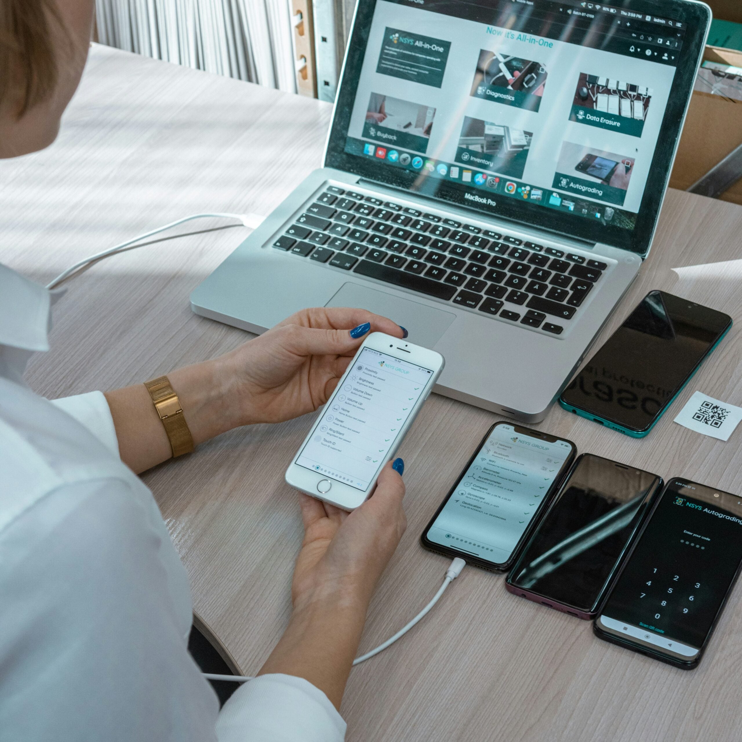 Person testing an app on phones and a laptop as part of quality assurance